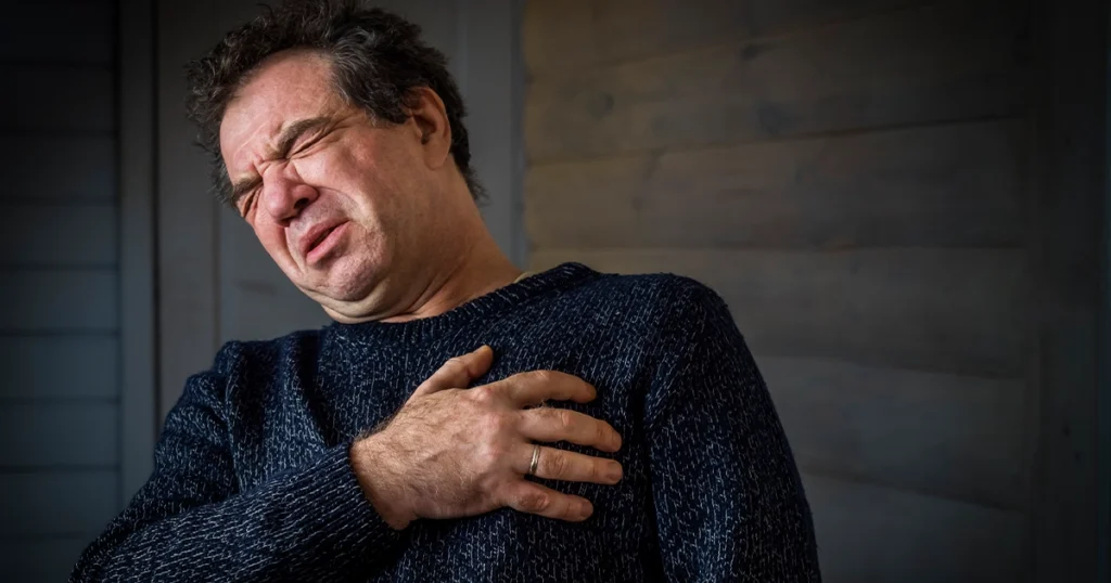 Man clutching chest in pain from anxiety episode.
