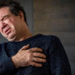 Man clutching chest in pain from anxiety episode.