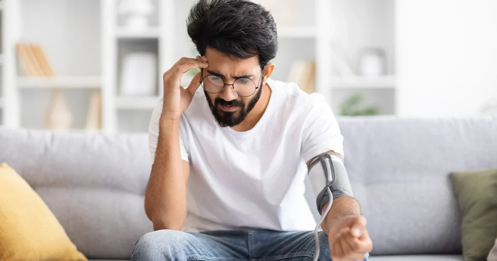 Man checking blood pressure while feeling dizzy from dehydration.