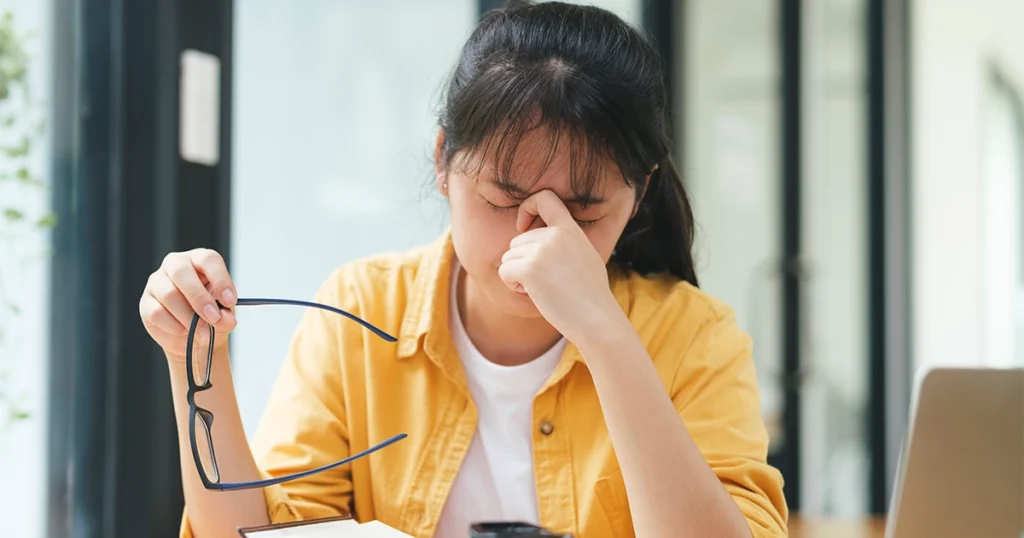 Woman rubbing her eyes while feeling fatigued and weak