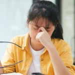 Woman rubbing her eyes while feeling fatigued and weak