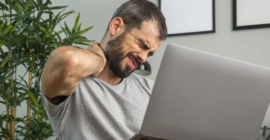 man-experiencing-neck-pain-while-working-from-home-laptop