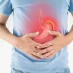 Man holding his stomach with a highlighted inflamed stomach area.