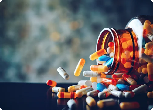 Pills spilling from a jar onto a table surface.