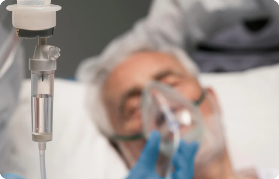 A hospitalized man in bed, receiving oxygen through a tube.