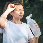 Woman feeling dehydrated and drinking water after exercise.