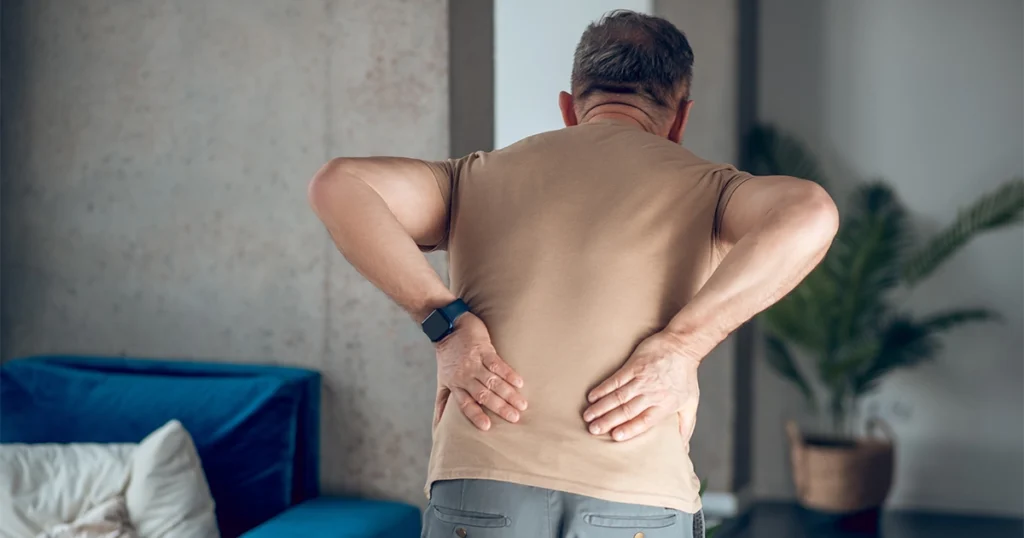 Man experiencing lower back pain while standing.