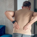 Man experiencing lower back pain while standing.