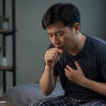 Sick man coughing and clutching chest.