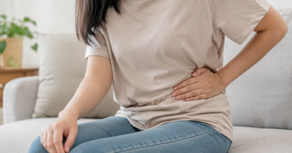Woman holding her lower left abdomen in pain.