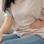Woman holding her lower left abdomen in pain.