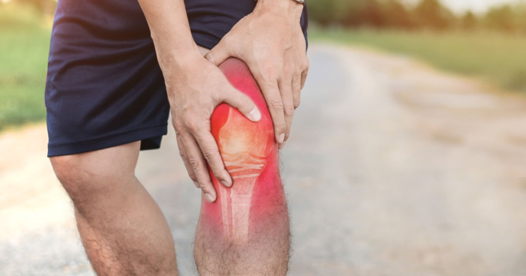 Person holding a painful knee with red inflammation highlight.