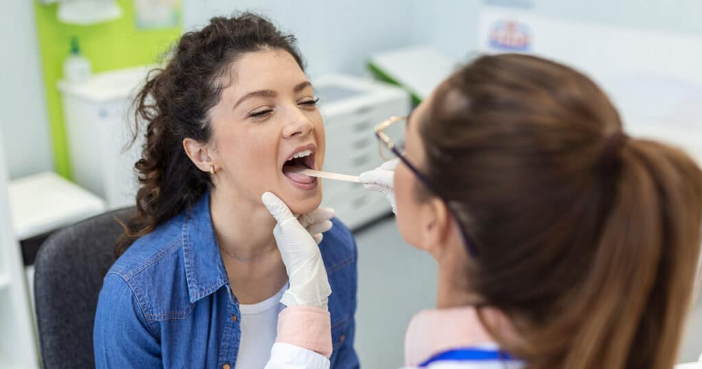Doctor examines a female patient’s throat