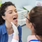 Doctor examines a female patient’s throat