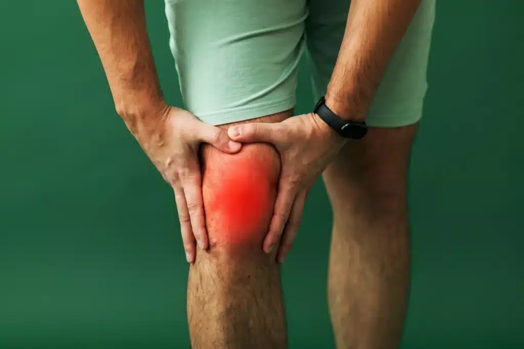 Person holding their knee with a red glow indicating pain.