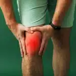 Person holding their knee with a red glow indicating pain.