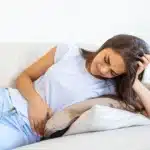 Woman lying on a sofa with severe lower abdominal pain.
