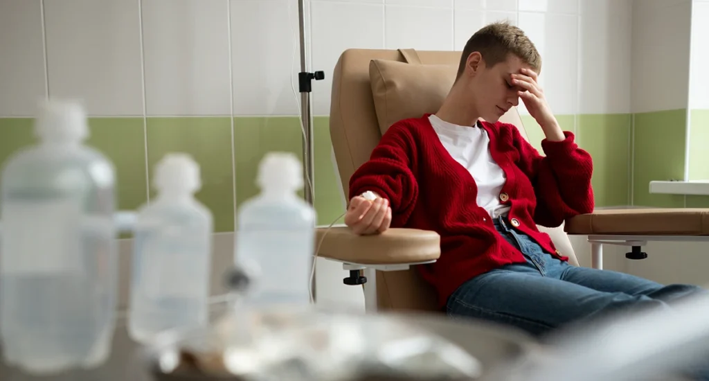 Patient sitting in a clinical chair receiving IV treatment.