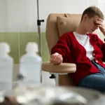 Patient sitting in a clinical chair receiving IV treatment.