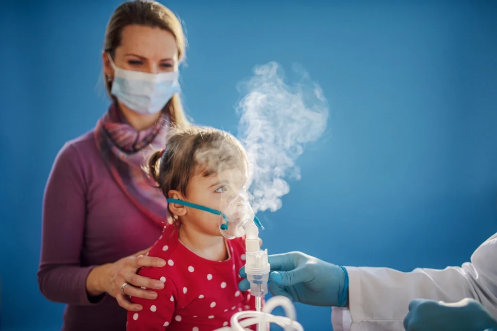 Young child using a nebulizer mask during a medical appointment.