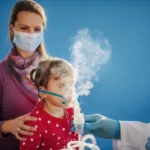Young child using a nebulizer mask during a medical appointment.