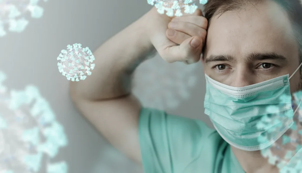 Exhausted man wearing a mask surrounded by viral particles.