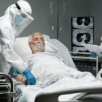 Medical workers in hazmat suits treating an elderly hospital patient.