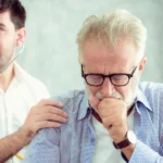 Doctor examining a coughing senior man.