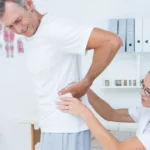 Doctor examining man with sciatica pain